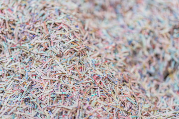 Close-up of multi-colored shredded paper, densely packed, in chaotic texture, bright lighting, realistic depiction.