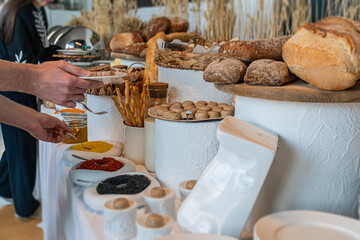 A kitchen filled with fresh baked goods, spreads, and one individual serving Rustic wooden panels, natural light, earthy tones, and a sense of calm orderliness