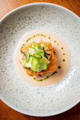 A beautifully plated dish features crispy elements, fresh cucumbers, and vibrant sauce