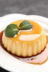 Delicious pudding with caramel sauce and mint on gray table, closeup