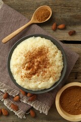 Delicious rice pudding with cinnamon and almonds on wooden table, flat lay