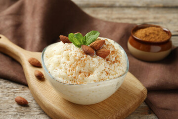 Delicious rice pudding with cinnamon, almonds and mint on wooden table, closeup