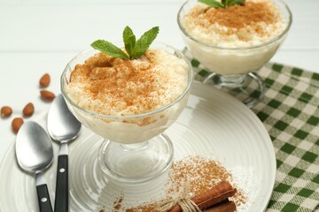 Delicious rice pudding with cinnamon, mint, almonds and spoons on table, closeup