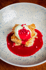 A stunning dessert of flaky pastry, mint ice cream, and vibrant raspberry sauce