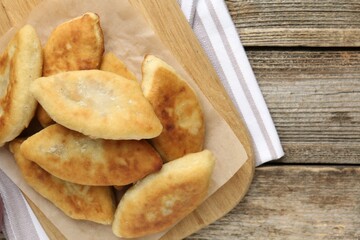 Delicious fried pyrizhky (stuffed pies) on wooden table, top view. Space for text