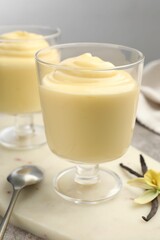 Tasty vanilla pudding, pods and flower on grey table, closeup