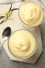 Tasty vanilla pudding, pods and flower on grey table, flat lay