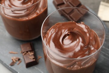 Tasty pudding and pieces of chocolate on grey table, closeup