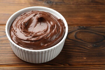 Tasty chocolate pudding in bowl on wooden table, closeup. Space for text