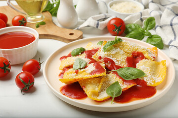 Delicious ravioli with tomato sauce, parmesan cheese and basil on white table, closeup