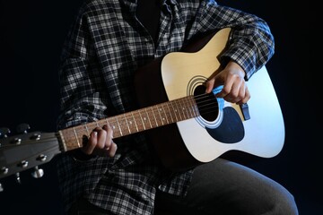 Fototapeta premium Woman playing guitar on black background, closeup