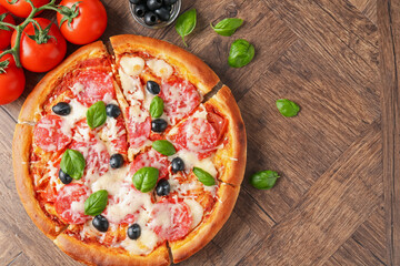 Tasty pizza and ingredients on wooden table, flat lay. Space for text