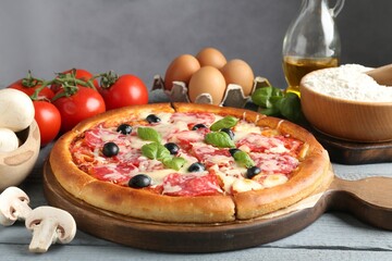 Tasty pizza and ingredients on grey wooden table, closeup
