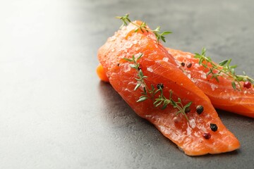 Seafood. Pieces of salmon fillet with spices on gray table, closeup. Space for text