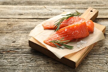 Seafood. Pieces of salmon fillet, rosemary and salt on wooden table