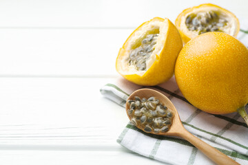 Ripe passion fruits and seeds on white wooden table, closeup. Space for text