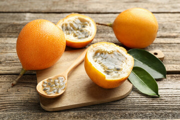 Ripe passion fruits, seeds and green leaves on wooden table, closeup