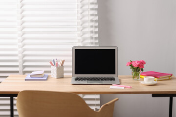 Workplace with laptop and beautiful flowers in office