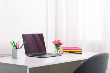 Workplace with laptop and beautiful flowers in office. Space for text