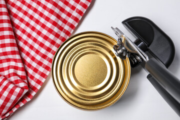 Can opener and tin on white wooden table, top view
