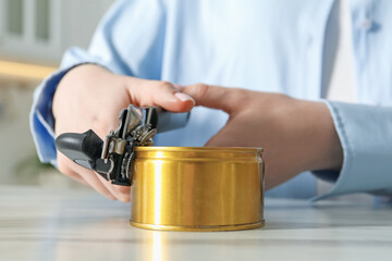 Woman opening tin with can opener at white marble table, closeup