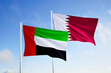 flags of qatar and united arab emirates over blue sky background.