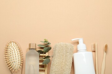 Loofah sponges, cosmetic products, toothbrushes, brush and eucalyptus branch on beige background,...