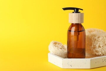 Natural loofah sponges and cosmetic product on yellow background, closeup. Space for text