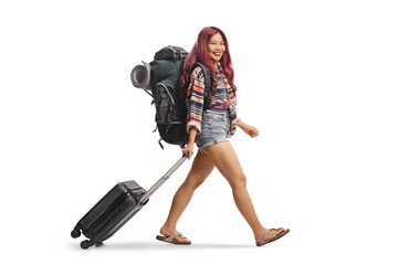Asian female tourist walking with a suitcase and looking at camera