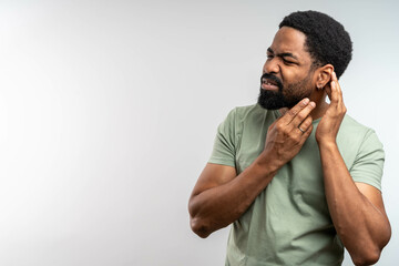 Man with earache is holding his aching ear body pain concept. Young man with hearing problems. male having ear pain touching his painful head isolated on gray background