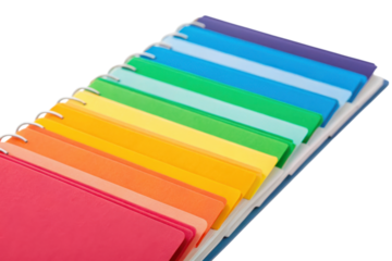 A stack of spiral-bound notebooks with colorful covers arranged in a gradient on a black background.