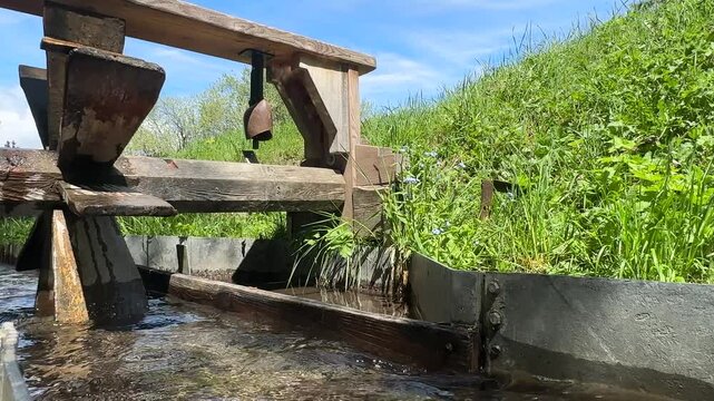 Historic Wooden Water Wheel Turning in a Sunlit Stream