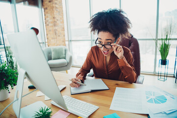 Confident businesswoman working in modern loft office space, analyzing reports and charts with...