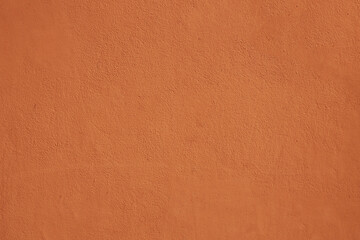 Textured background. Decorative plaster wall, external of facade. Texture of red pink peach fuzz stucco plaster wall of clay house structure background. Brown yellow clay mud cement texture pattern