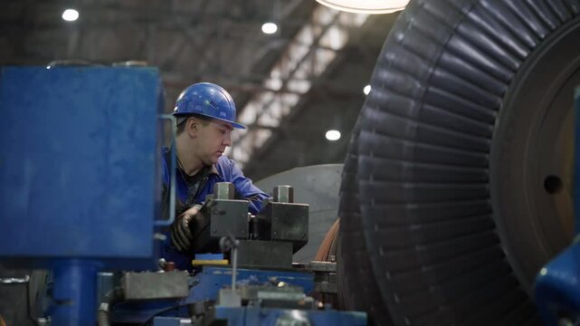 A Worker is inspecting the turbine generator produced at the manufacturing plant. A Worker is examining the parts of the turbine generator. A Worker is testing the quality of the turbine generator.