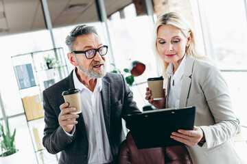 Business professionals discussing workplace projects while enjoying coffee in a coworking modern office environment