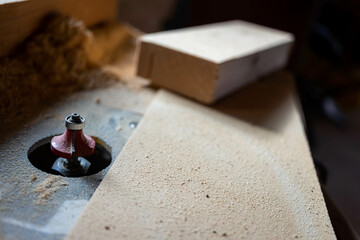 Red sharp router bit in a small woodworking shop, space for text.