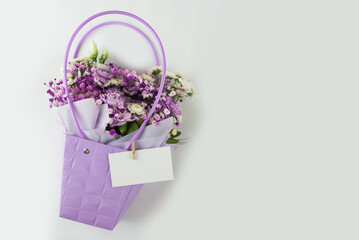 Bouquet of different purple flowers in a gift bag on a white background. Gift for a holiday, Women's Day, Wedding.