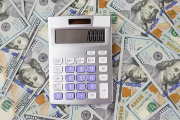 the calculator is lying on top of the dollars