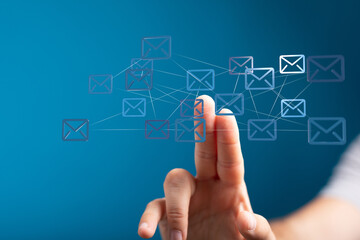 Hand interacting with a digital network of email icons.  Concept of global communication and connectivity.