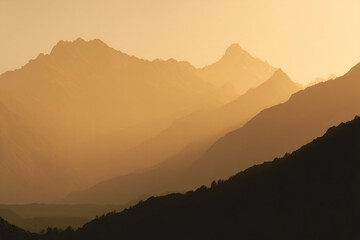 Obraz premium 015-049-Clouds-072-_distant_mountain_range_silhouetted_by_golden_li