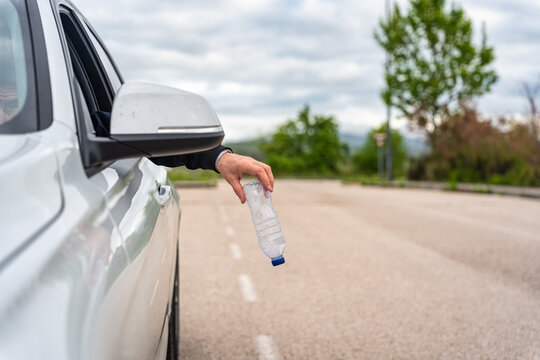 Man throwing a used plastic bottle of water out of his car and polluting the environment
