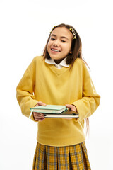 Stylish schoolgirl poses happily in a vibrant studio setting with books in hand