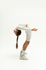 A girl showcases her flexibility in a trendy outfit while posing creatively in a studio