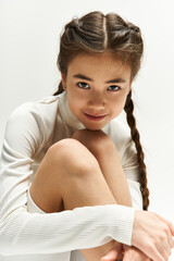 Stylish teenage girl in modern sportswear poses playfully in a bright studio setting