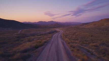 Dusty road winding through a valley at sunset.