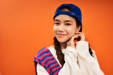 Teenager expresses playful confidence in stylish outfit against bright orange backdrop