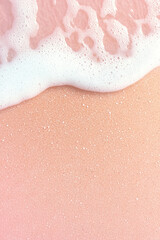 Pink sand beach with gentle waves and white foam creating serene and dreamy atmosphere