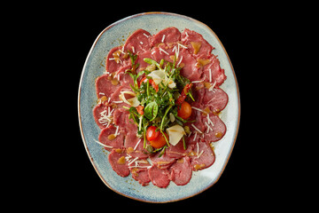 Culinary delight featuring thinly sliced beef carpaccio with fresh greens and cherry tomatoes on an elegant plate