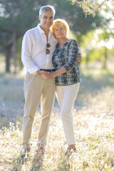 Fototapeta premium Happy senior couple holding hands and embracing in nature